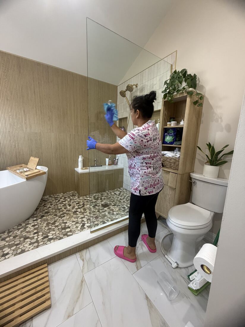Jenny cleaning a glass shower panel in a bathroom