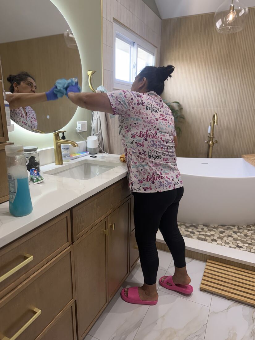 Jenny cleaning a bathroom vanity and mirror